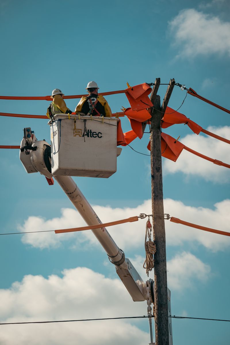 Lineworkers in an elevated bucket maintaining overhead distribution lines with protective equipment