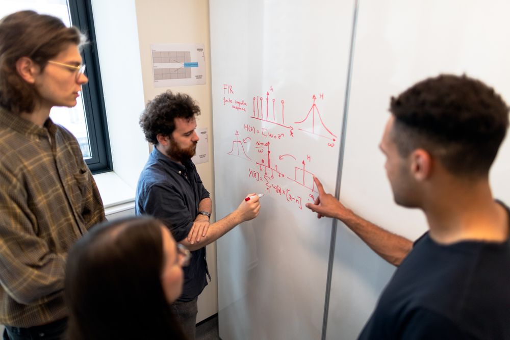 Engineers working through technical concepts together at a whiteboard